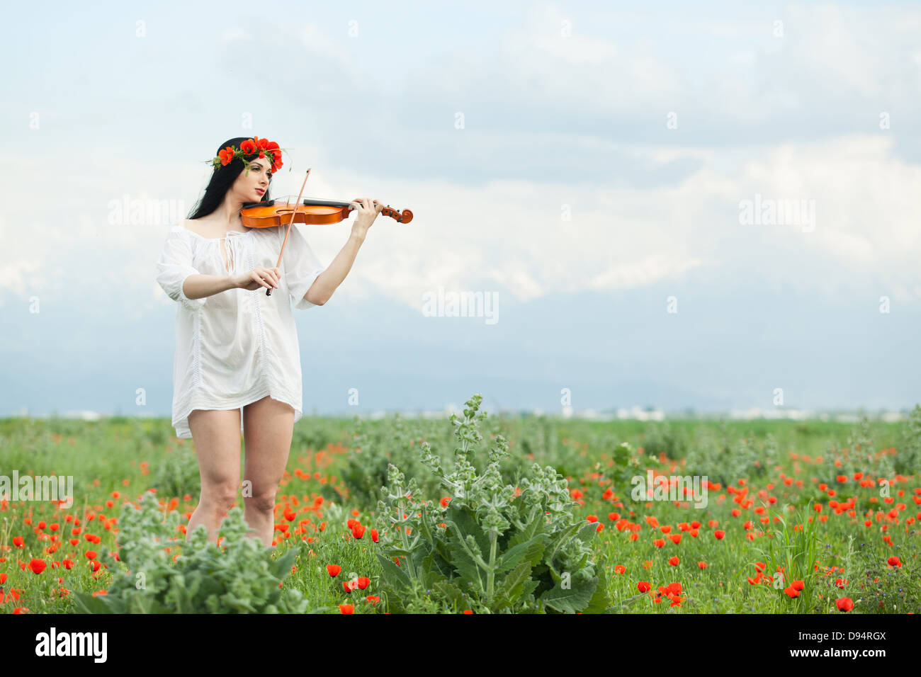 A girl with a violin in a white shirt on a poppy field Stock Photo