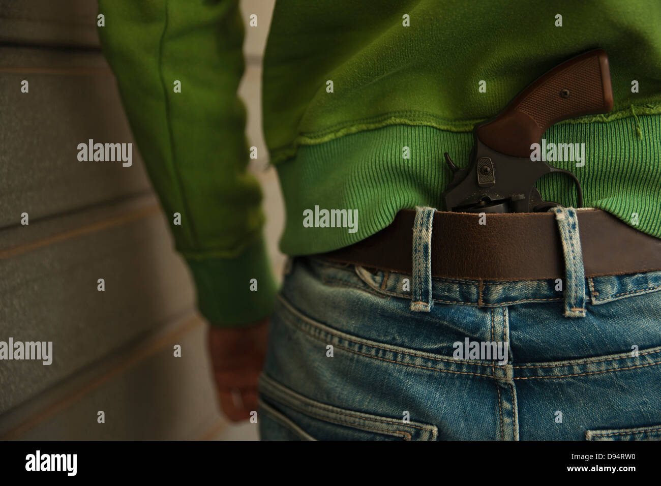Close-up of Back of Young Man with Handgun Tucked into Waistband of Blue Jeans, Mannheim, Baden-Wurttemberg, Germany Stock Photo