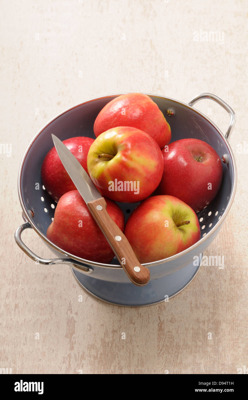 Overhead View of Colander filled with Red Apples and a Knife on Beige ...