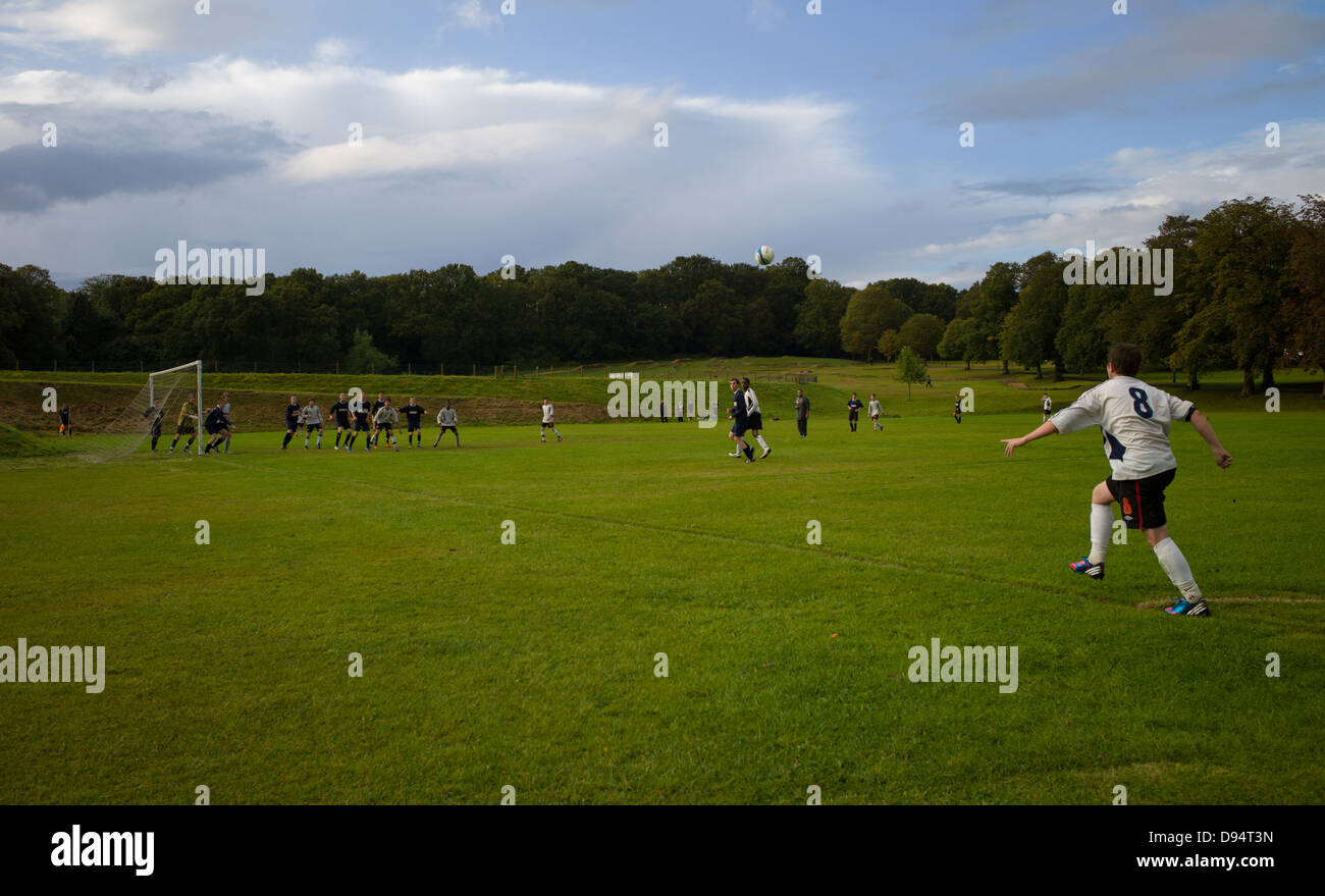 a local park football match a ball is crossed in from a corner Stock