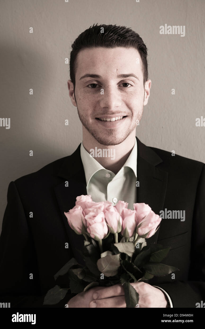 Portrait of Young Man holding Bouquet of Pink Roses, Looking at Camera ...