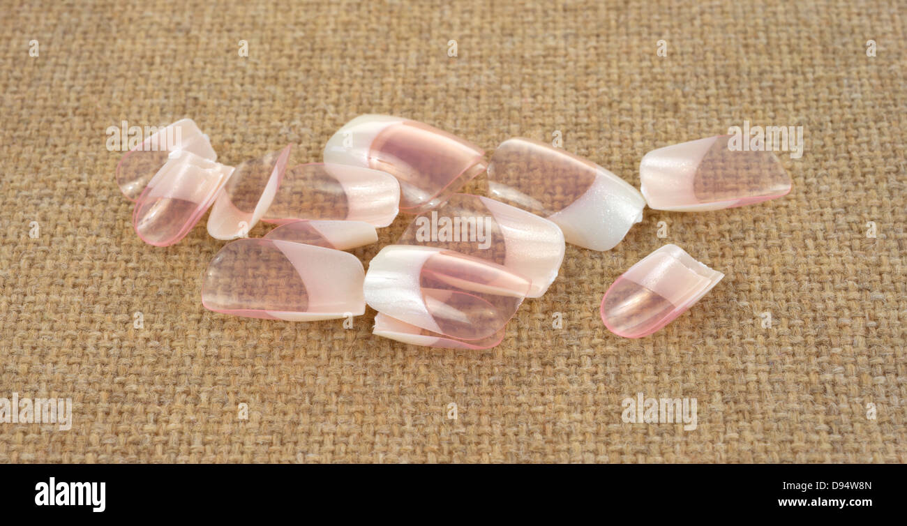 Several false fingernails on a brown cloth background. Stock Photo