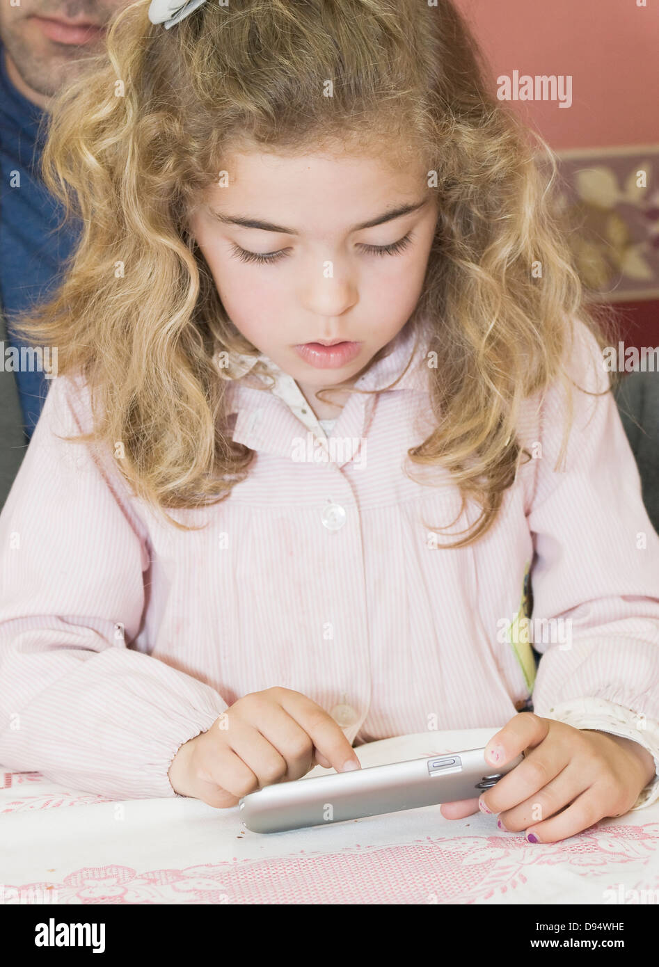 Little girl using a smartphone. The photo depicts the use of new technologies by children. Stock Photo