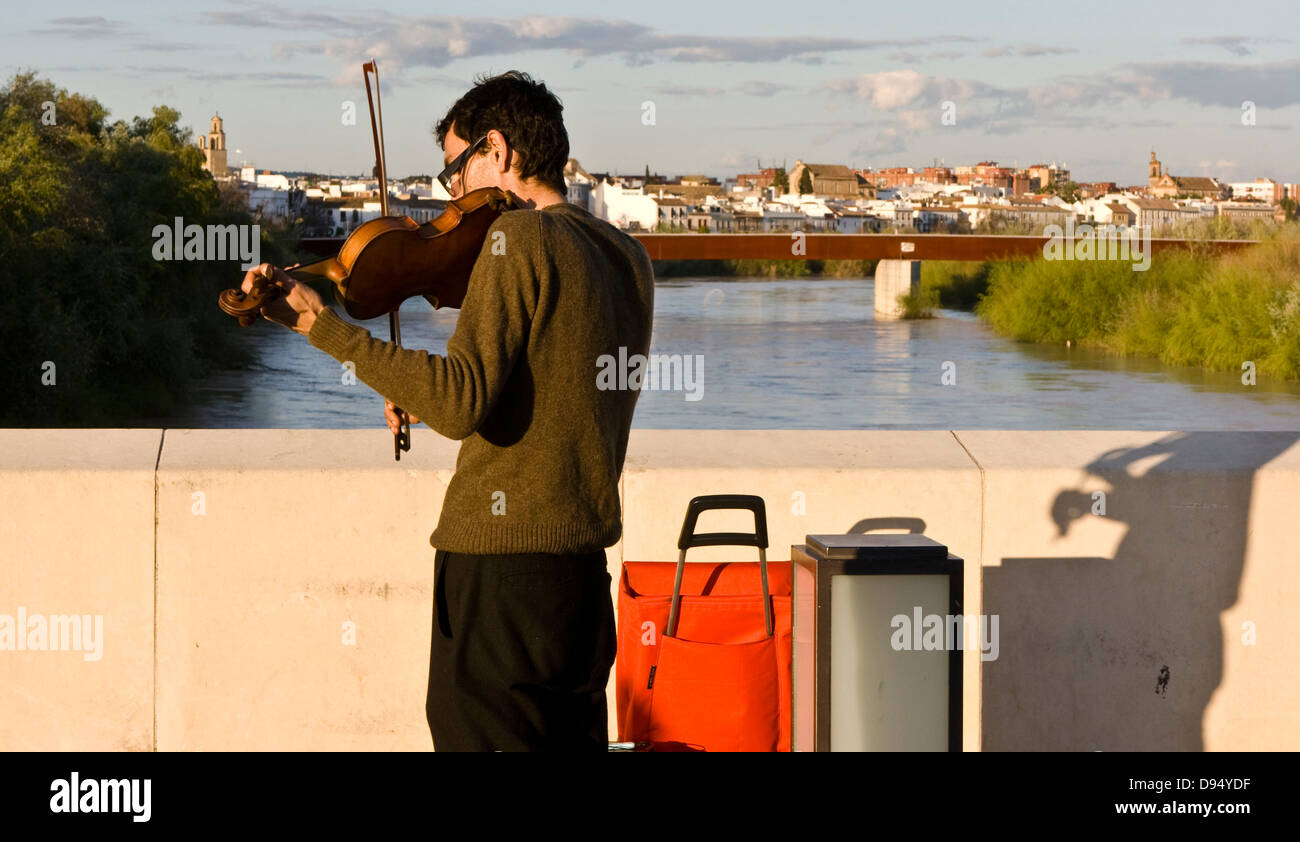 Street entertainer busker playing a violin on the Roman bridge in Cordoba at sunset Andalusia Andalucia Spain Europe Stock Photo