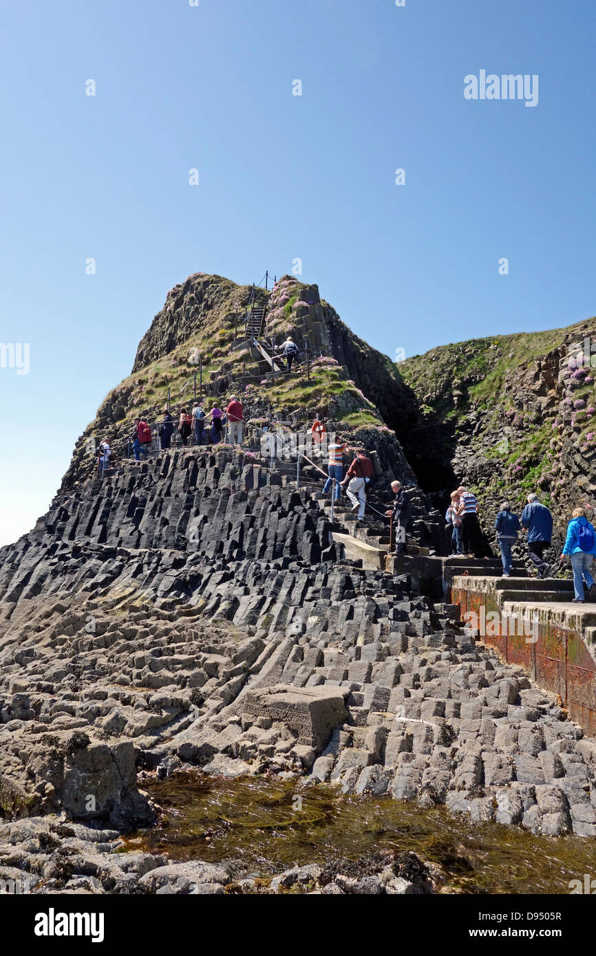 Passengers are making their way from the pier on the narrow path towards Fingal's Cave on the island of Staffa in Scotland Stock Photo