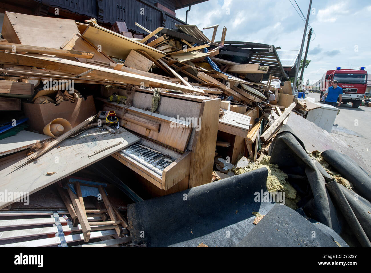 A severely damaged piano is situated in a pile of wreckage after floods