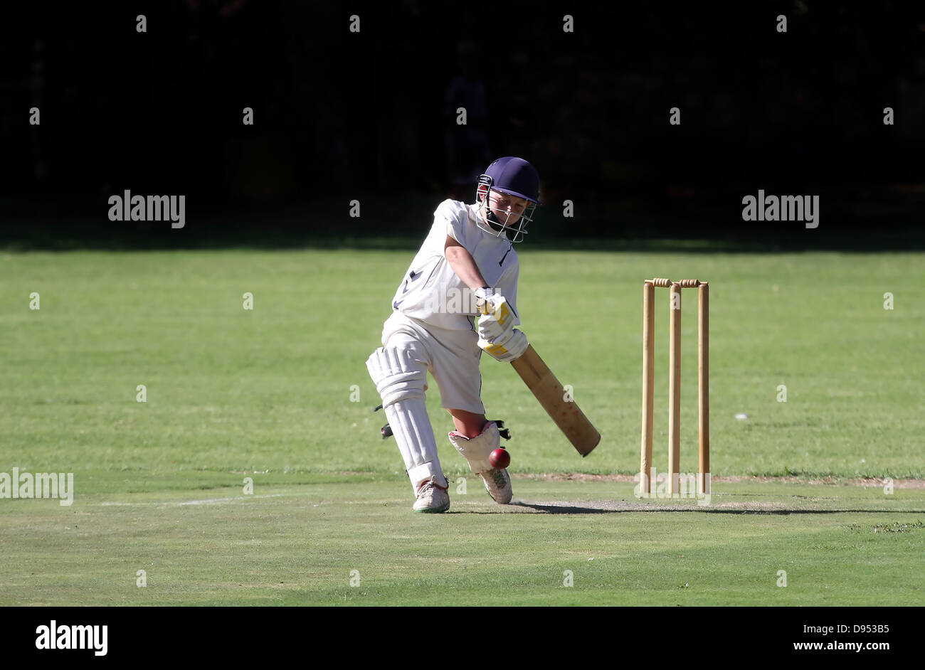 A young boy playing a straight drive cricket shot Stock Photo
