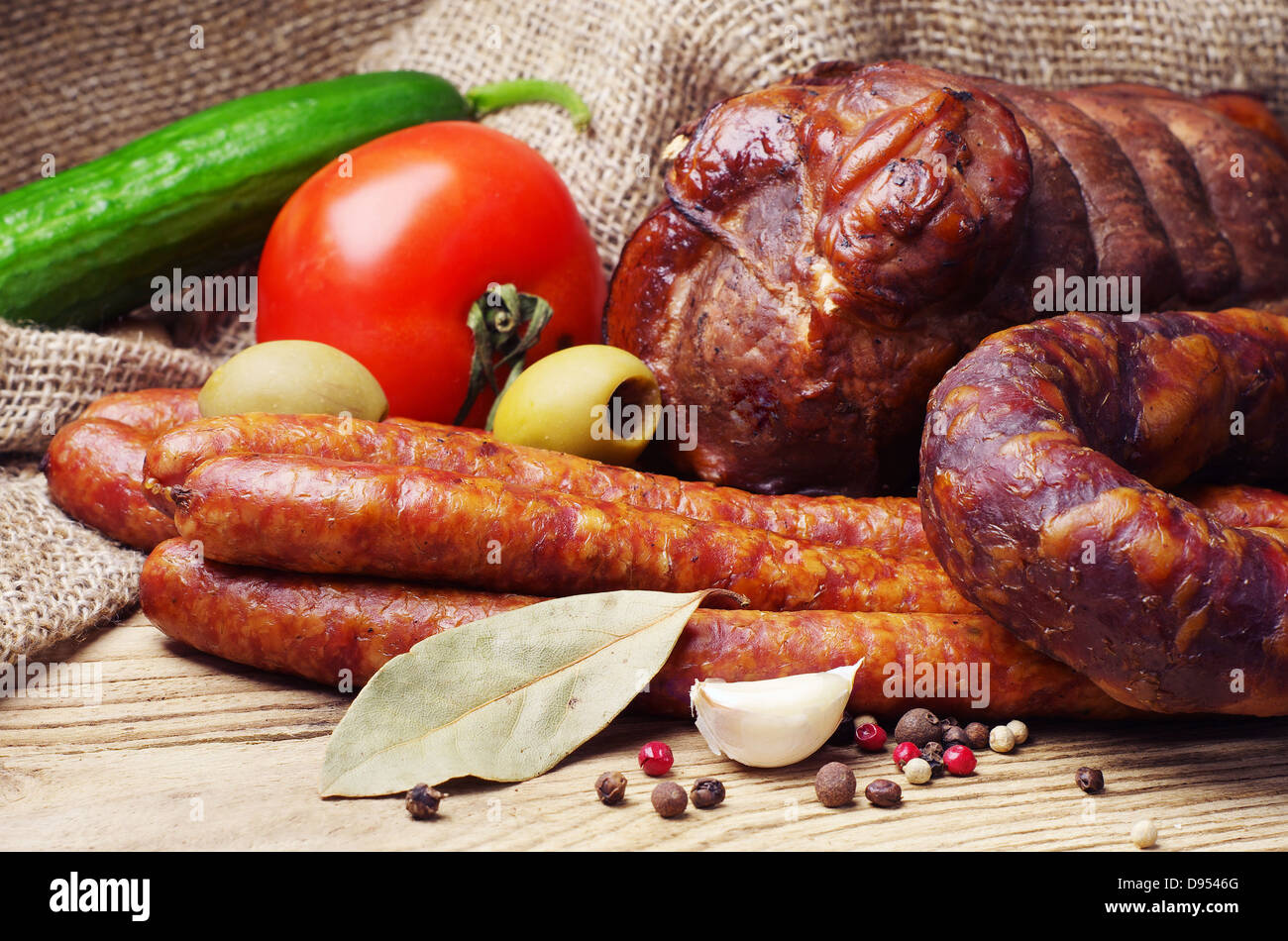 Smoked sausage, meat and vegetables on wooden table Stock Photo