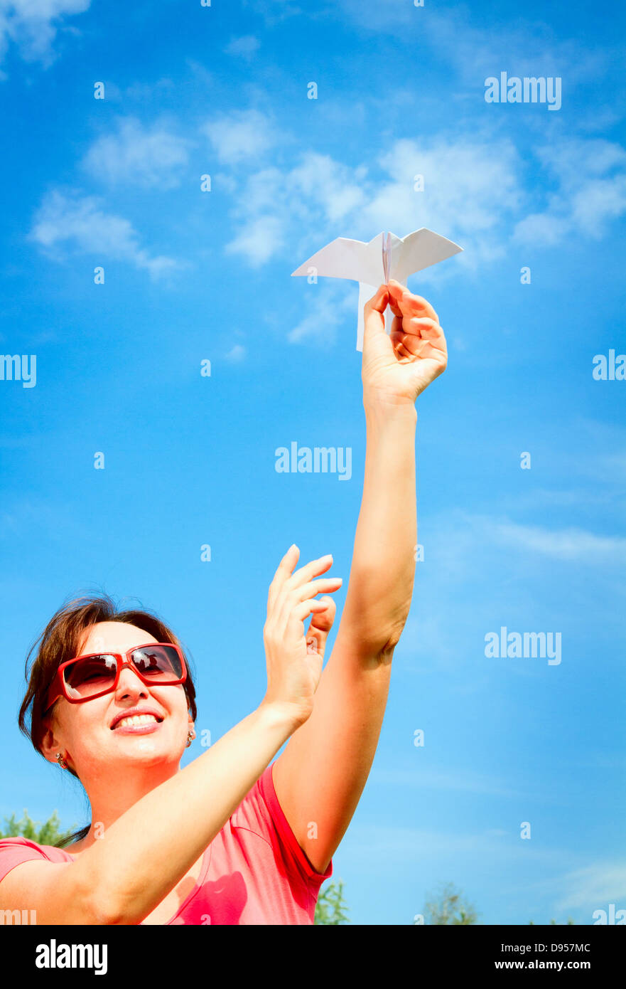 portrait of a beautiful woman starts paper plane in blue sky. Concept ...
