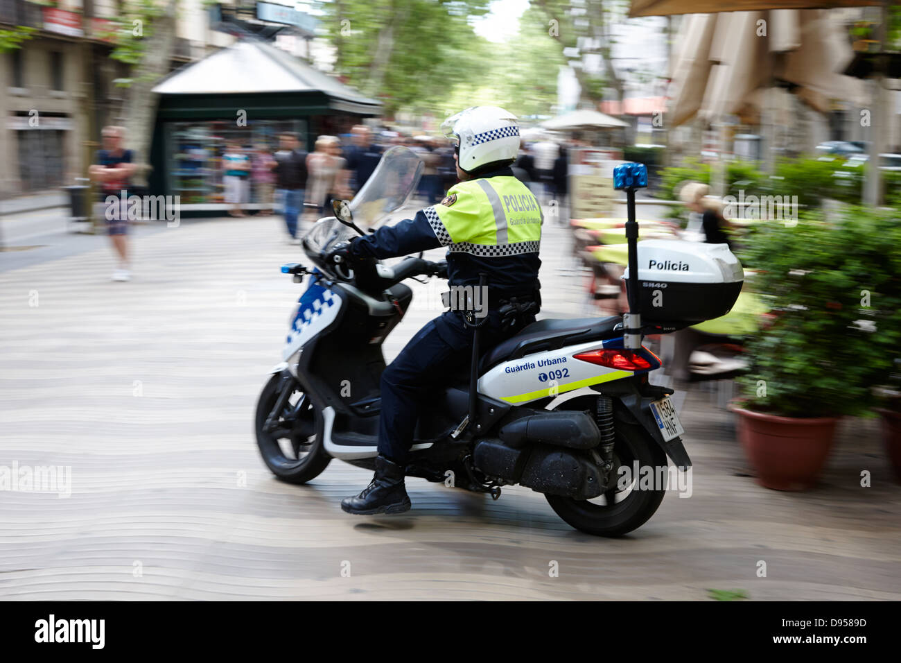 guardia urbana police officer on scooter patrolling la rambla city centre  of barcelona catalonia spain deliberate motion blur Stock Photo - Alamy