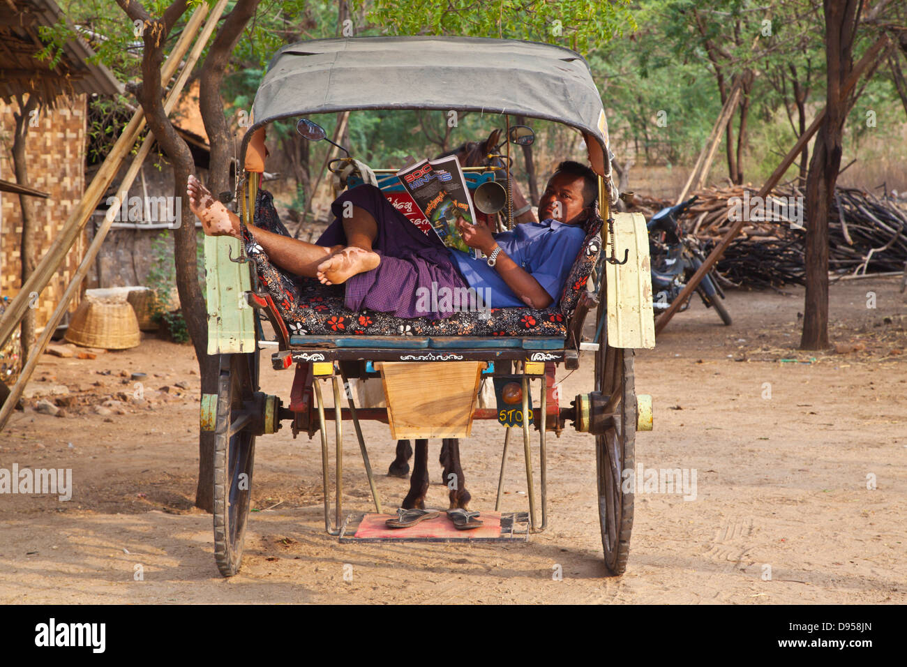 A HORSE CART DRIVER reads the newspaper while waiting for his client