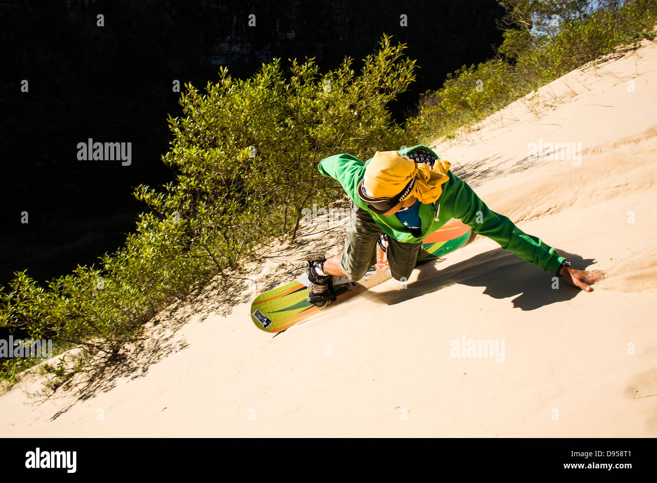 Young man sandboarding on the dunes of Morro dos Conventos Beach. Stock Photo
