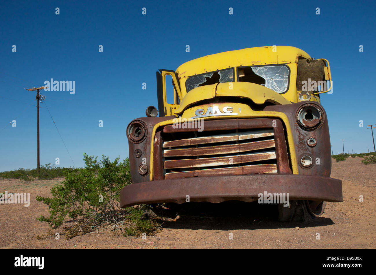 An iconic yellow US school bus lays abandoned in the deserts of Texas, USA. Stock Photo