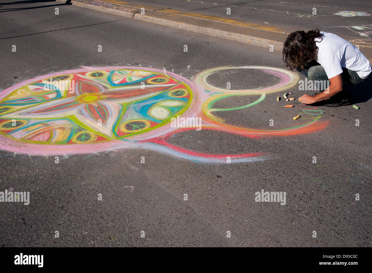 Artist draws a chalk design on the roadway in Missoula, Montana.  The community event was called sunday streets. Stock Photo