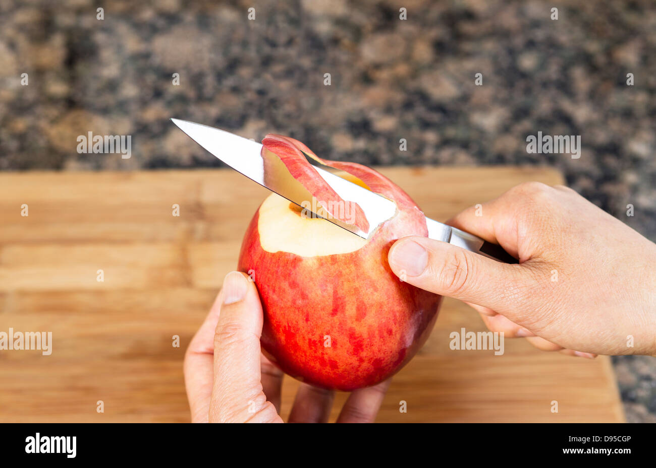 Female hands peeling fresh apple with paring knife with bamboo cutting