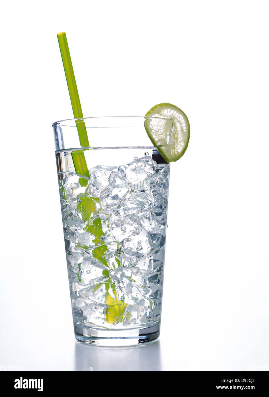 Vertical photo of a tall glass of water with ice cubes, slice of lime and a green straw on a white background Stock Photo