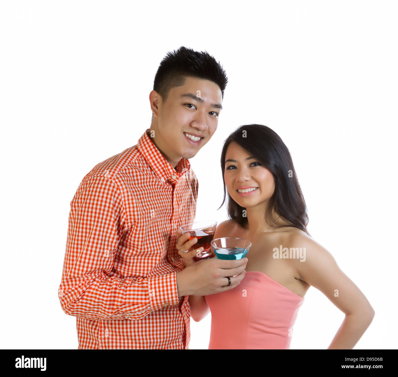 Photo of young adult couple holding mixed drinks while smiling on white background Stock Photo