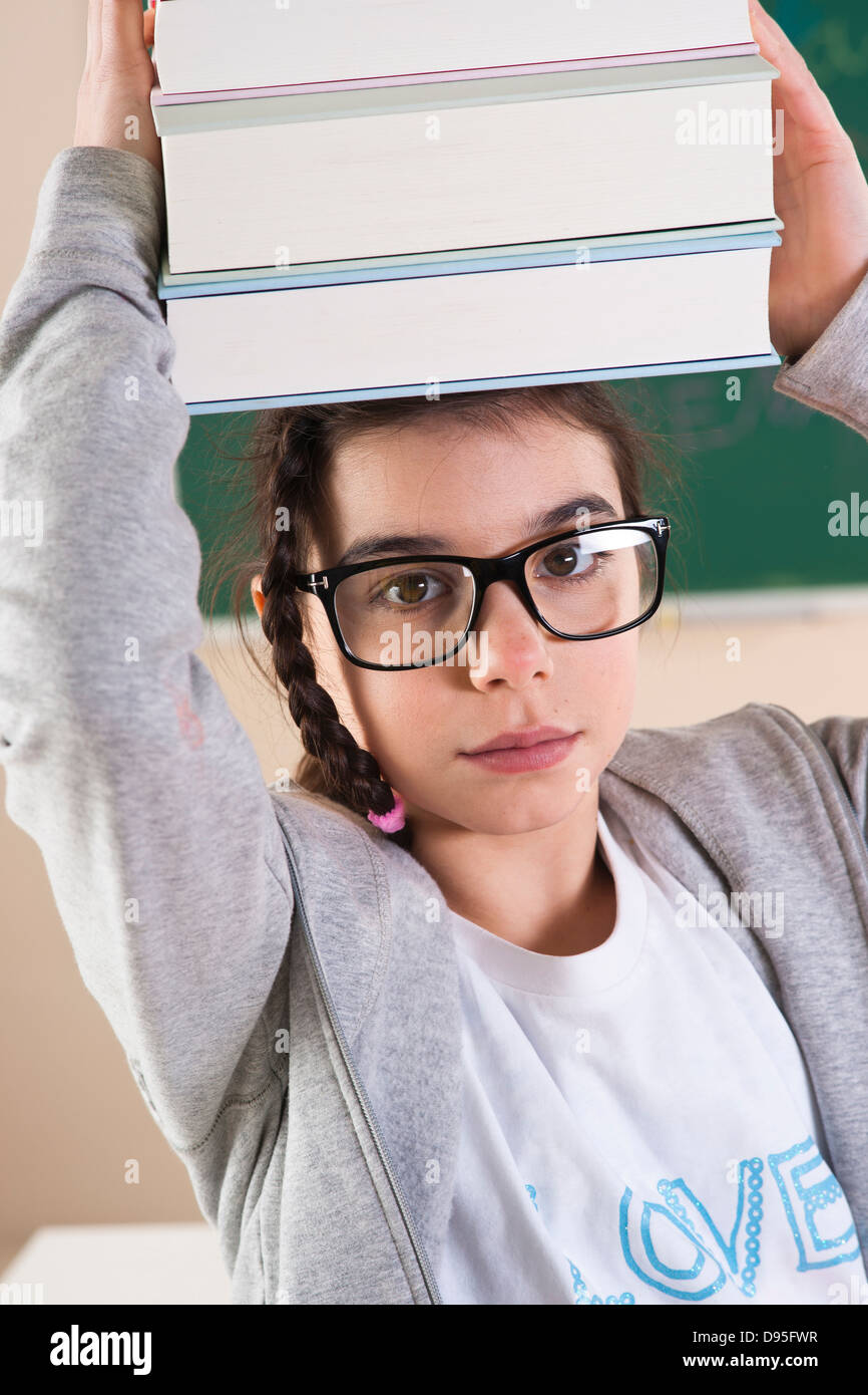 Girl Carrying a Stack of Books on her Head in Classroom Stock Photo - Alamy