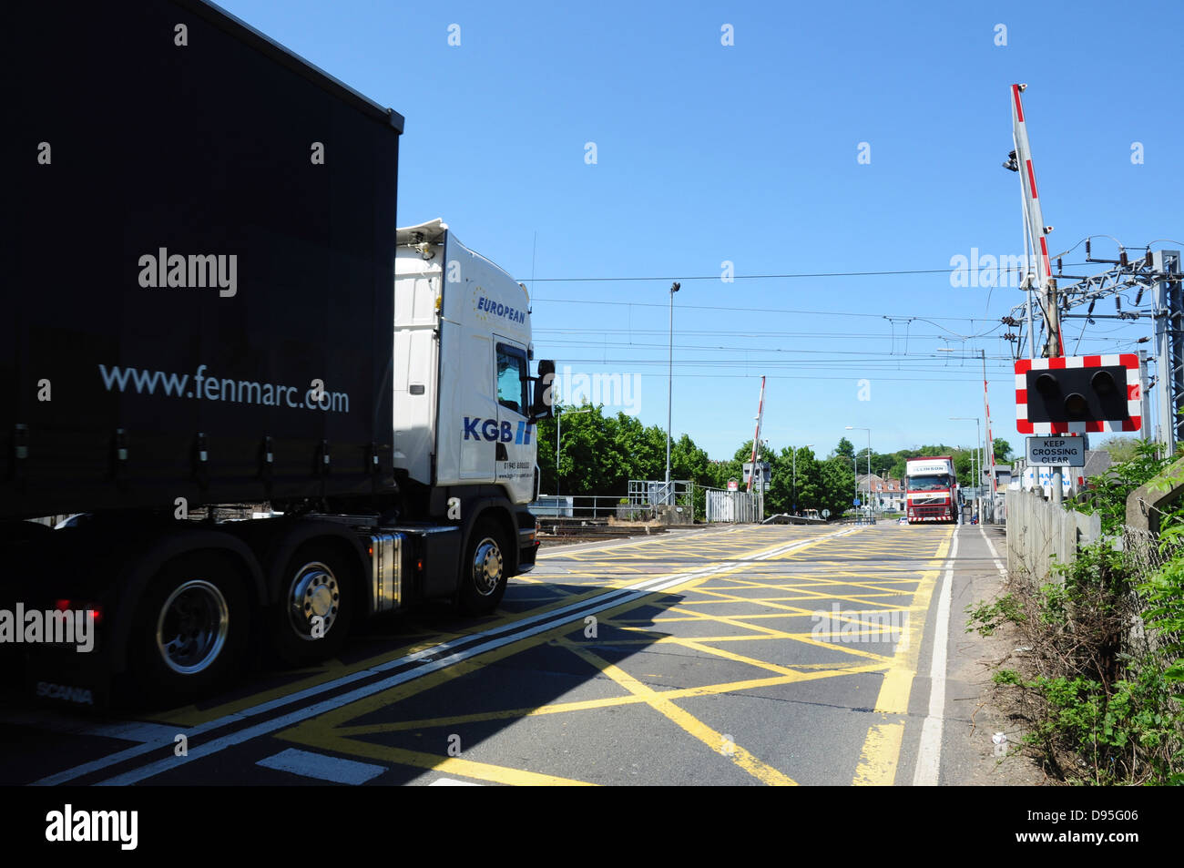 Heavy goods road vehicles at the railway level crossing in Ely, Cambridgeshire, England, UK Stock Photo