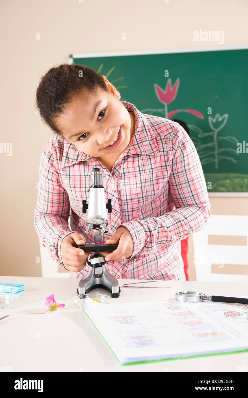 Girl Looking at Flower with Microscope in Classroom, Baden-Wurttemberg, Germany Stock Photo