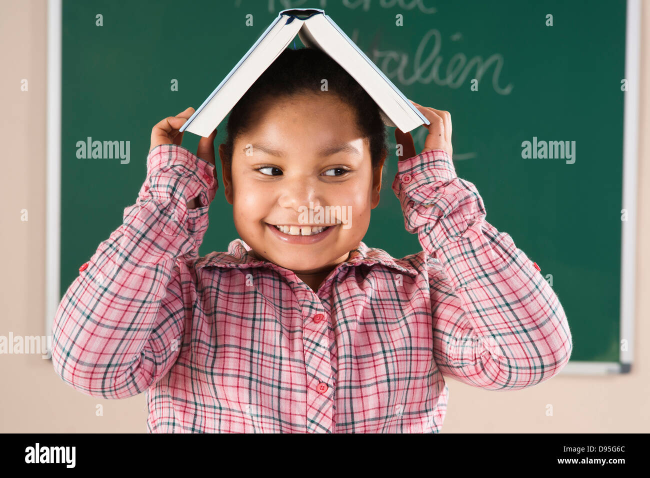 Girl With Textbook on her Head in Classroom, Baden-Wurttemberg, Germany Stock Photo