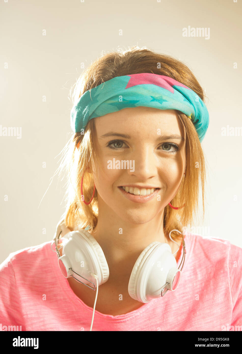 Head and shoulders portrait of teenage girl wearing a headband and headphones in studio. Stock Photo