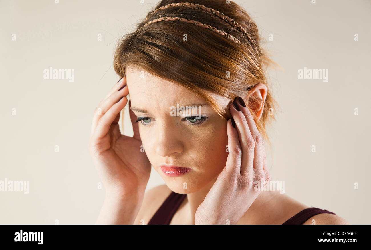 Head and shoulders portrait of teenage girl with hands on her head in studio. Stock Photo