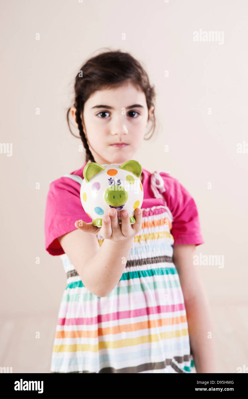 Portrait of Girl holding Piggy Bank in Studio Stock Photo - Alamy
