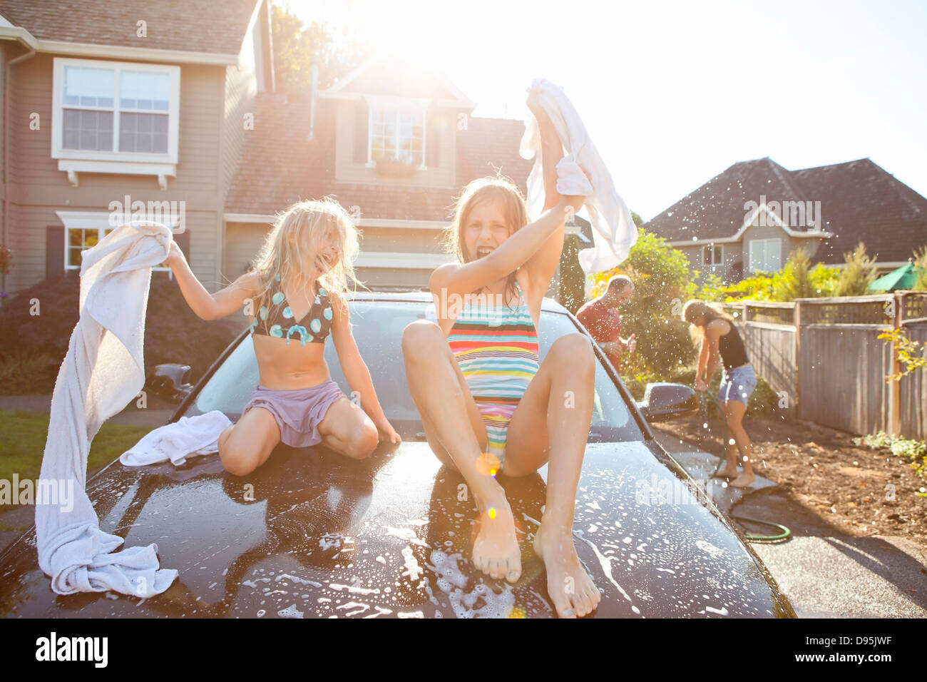 A family washes their car in the driveway of their home on a sunny summer afternoon in Portland, Oregon, USA Stock Photo