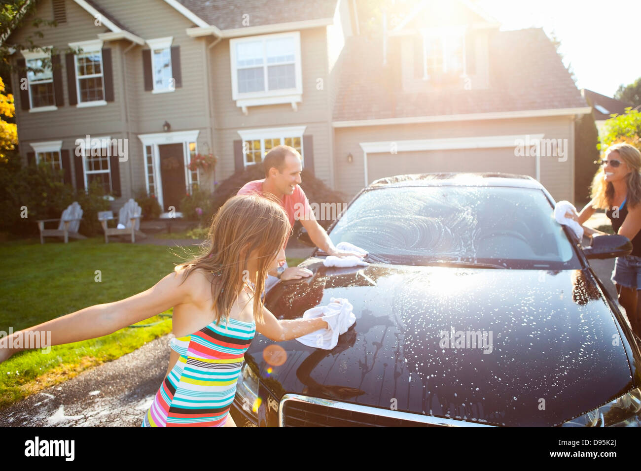 Family washing their car in the driveway of their home on a sunny summer afternoon in Portland, Oregon, USA Stock Photo