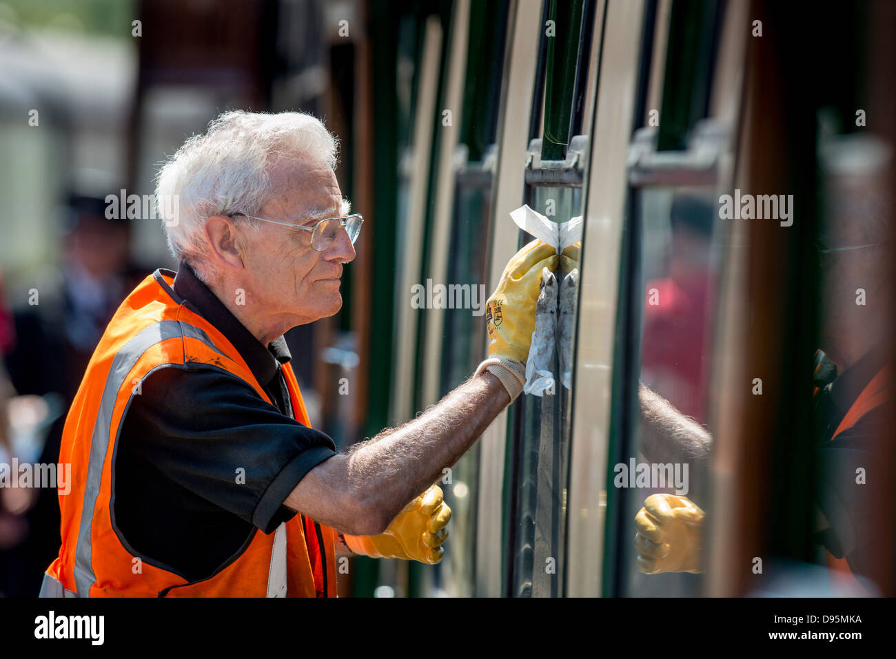 The Bluebell Railway in East Sussex, UK. The first standard guage steam preservation railway.A volunteer cleaning windows. Stock Photo