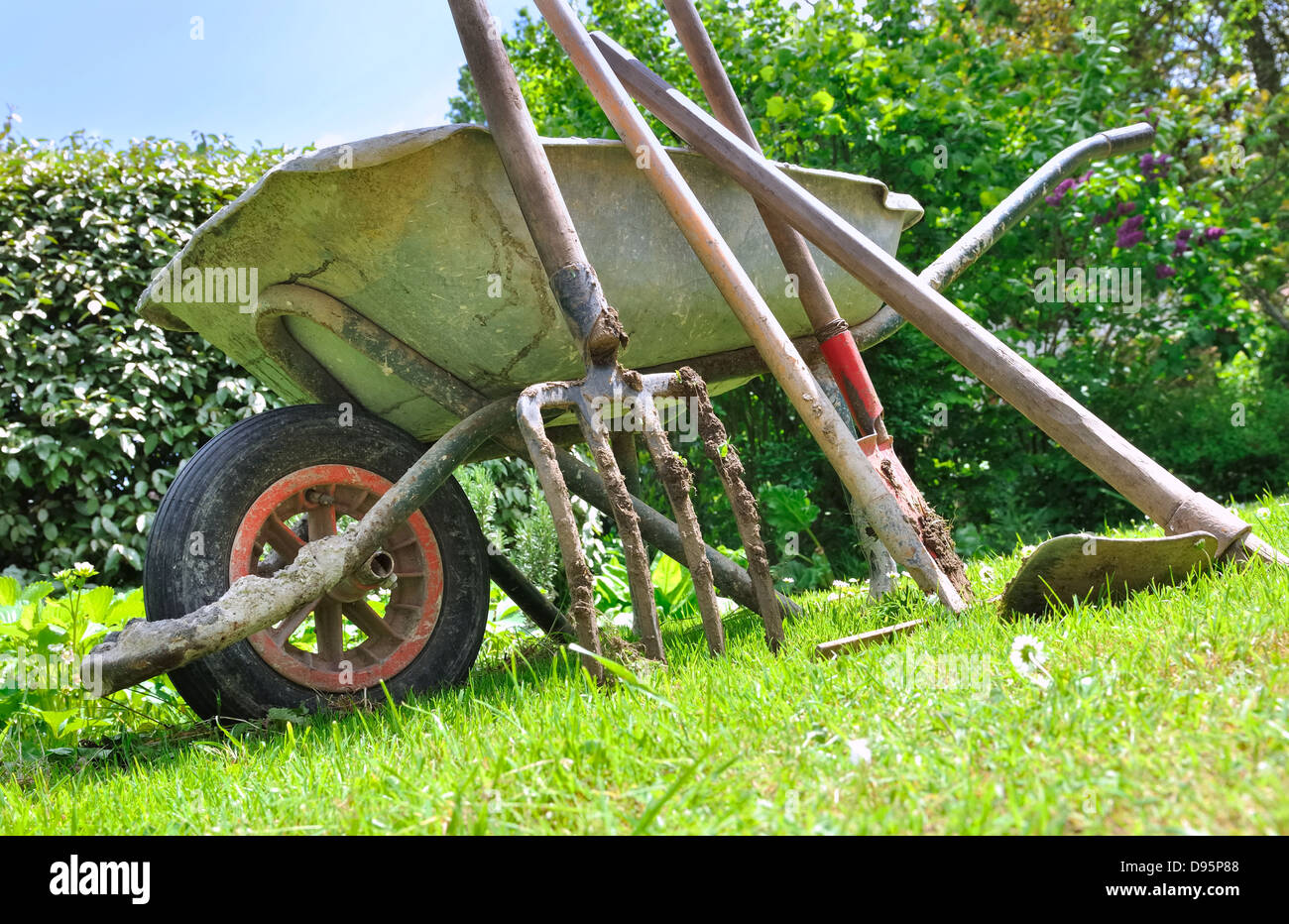 old gardening tools and wheelbarrow in the garden Stock Photo Alamy