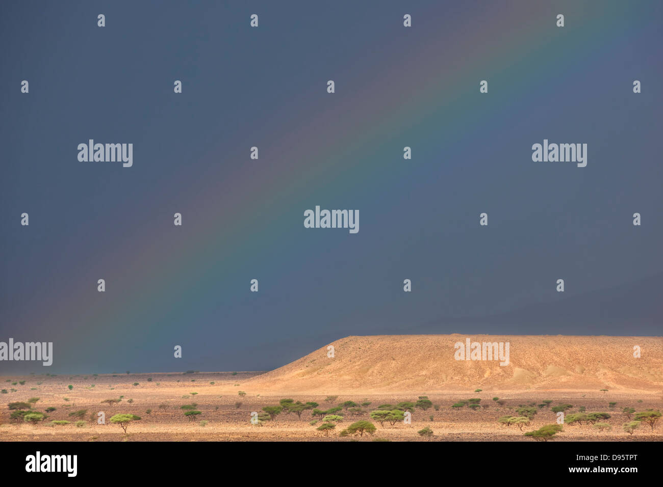 Rainbow on dark rainy sky in the Sahara desert of Morocco. Stock Photo