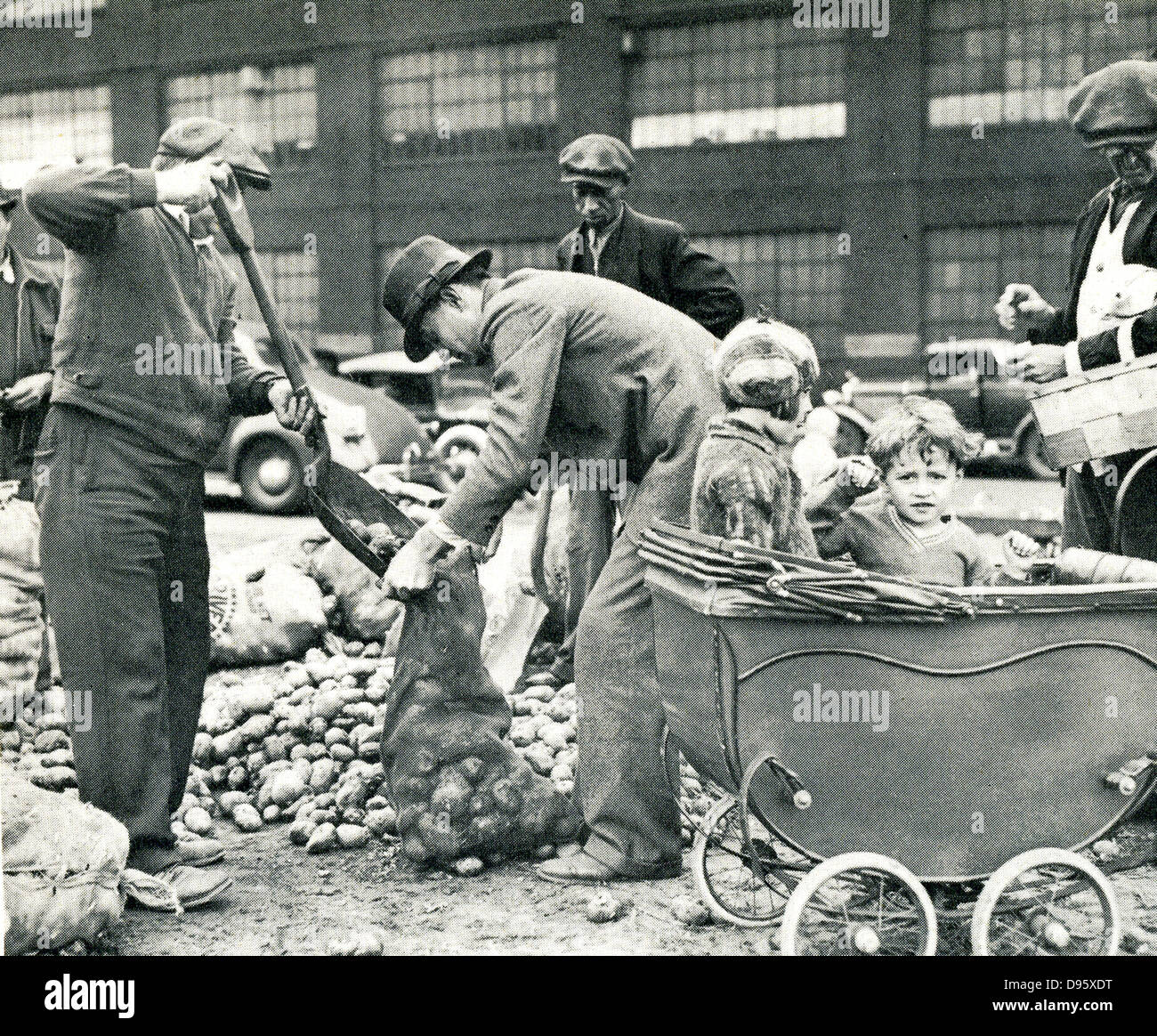 The American Depression - 1930s. Children faced starvation when local relief funds were exhausted and there was no work for their parents. Emergency food depots were set up.  Here two children in Cleveland wait while their father collects a ration of potatoes. Stock Photo