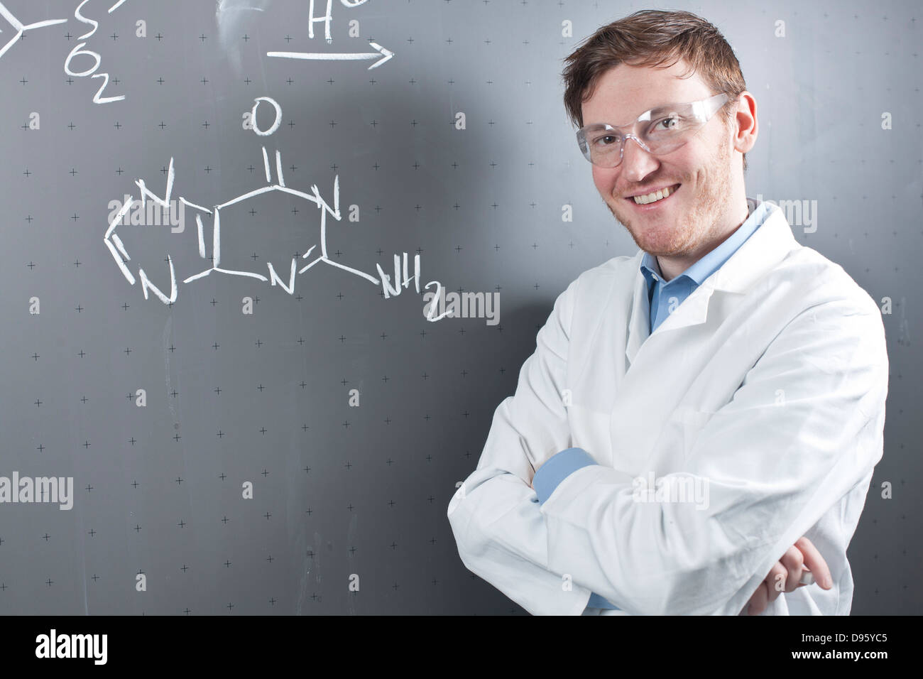 Germany, Portrait of young scientist standing next to chemical equation
