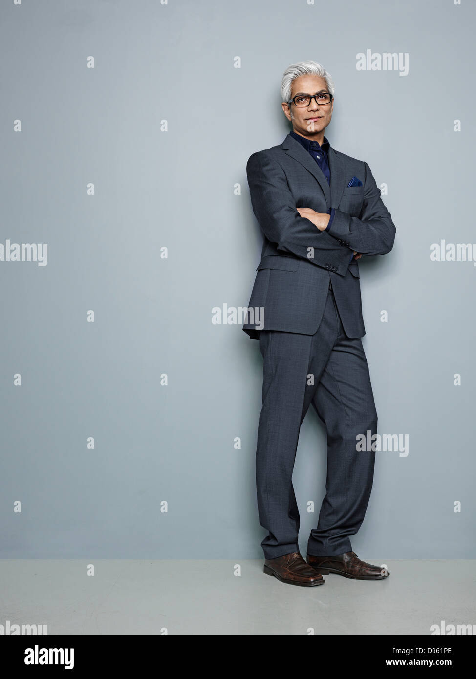 Businessman leaning on wall with arms crossed Stock Photo - Alamy