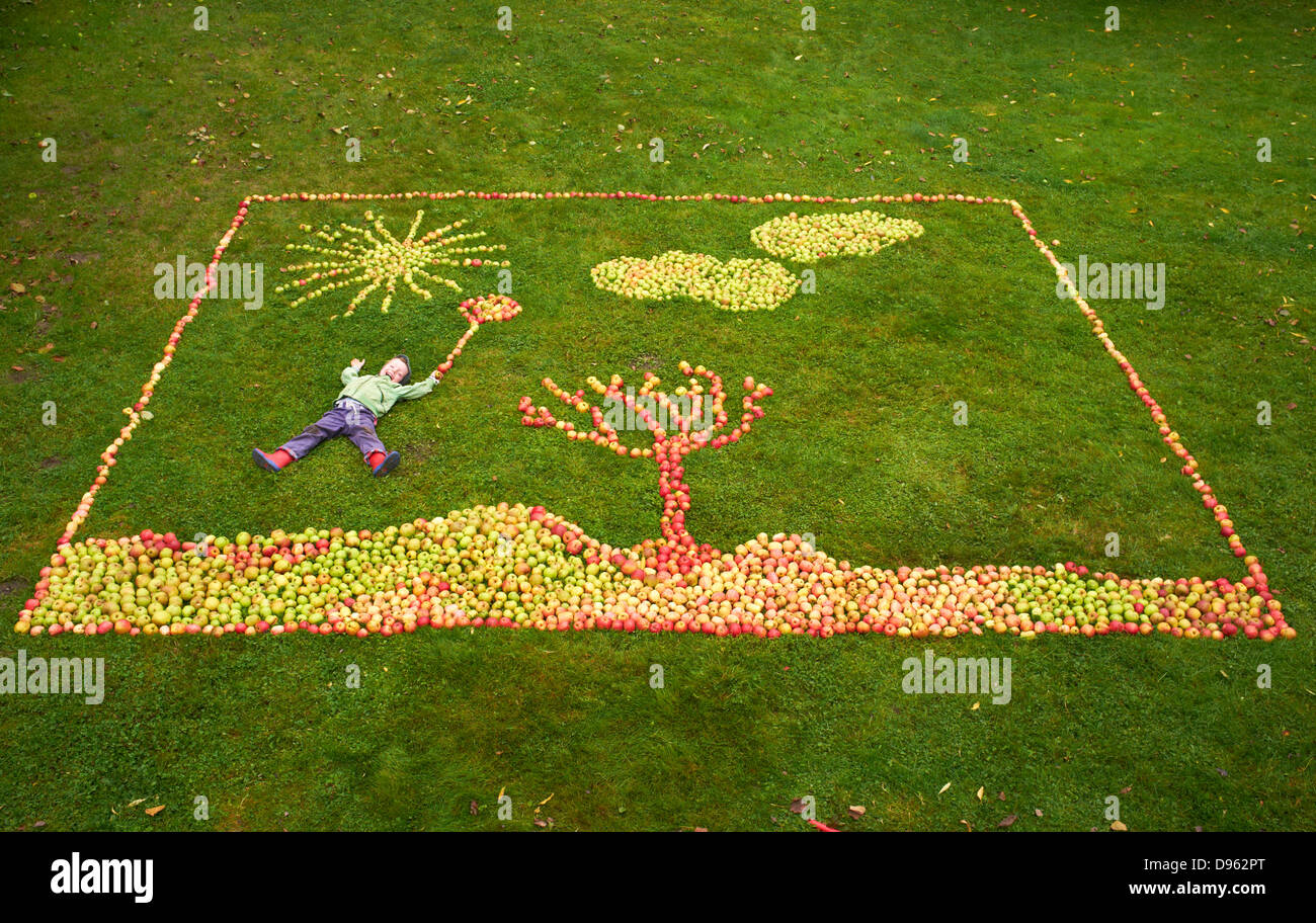 Germany, Boy lying on apples framing picture Stock Photo