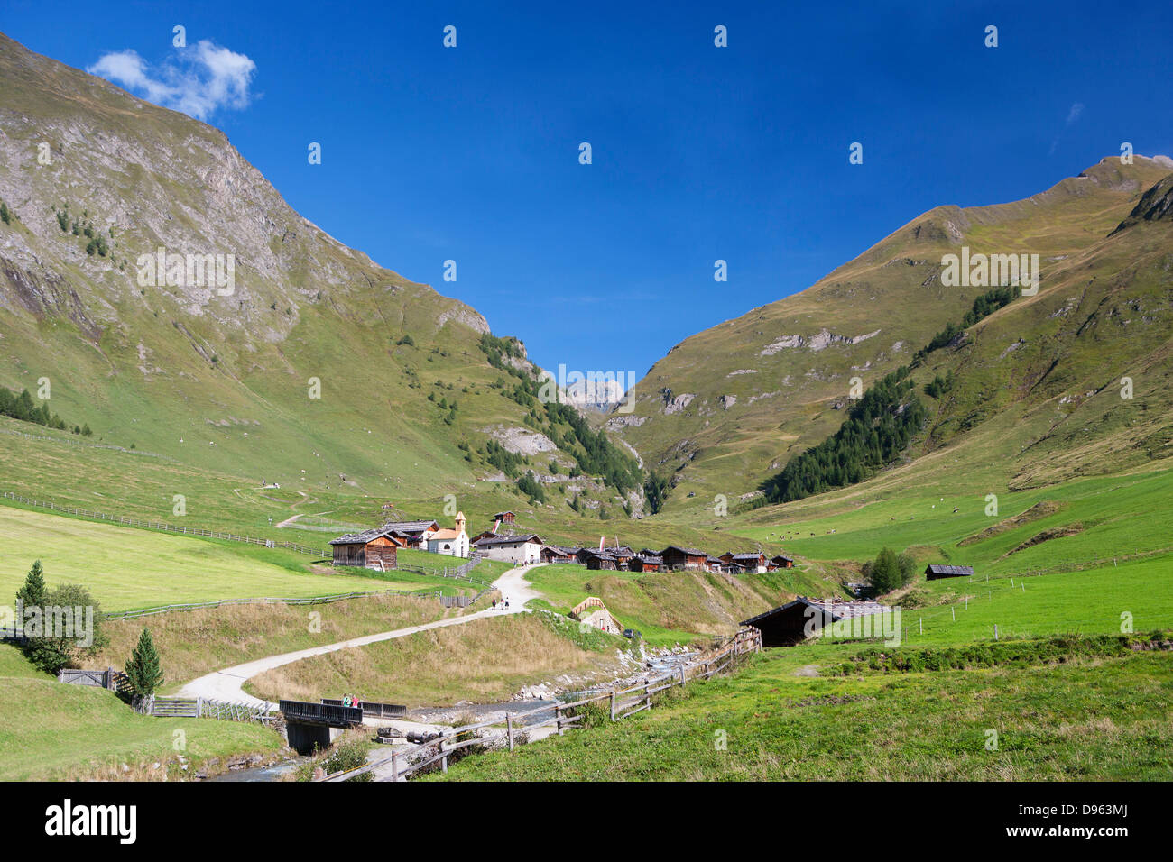 Italy, View of Pfunderer Berge with hikers crossing bridge near mountain village Stock Photo