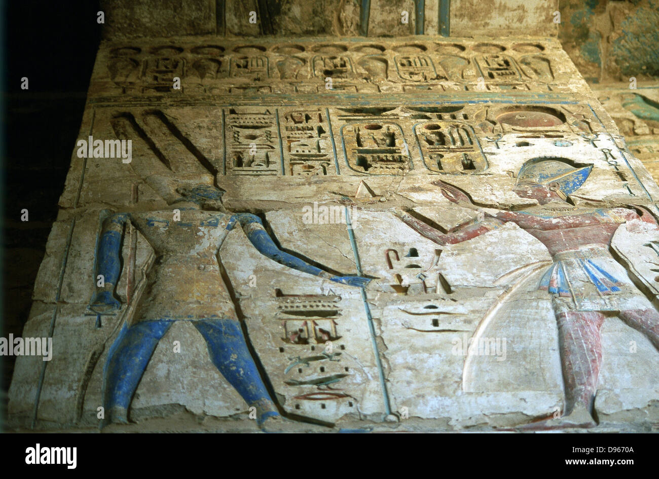 Amon-Ra, Egyptian god, (left) and Rameses III (1198-1167 BC) second king of 20th dynasty. Painted relief, temple of Rameses II, Medinet Habu. Ankh held by Amon-Ra. Empty Eye of Horus bottom centre. Stock Photo
