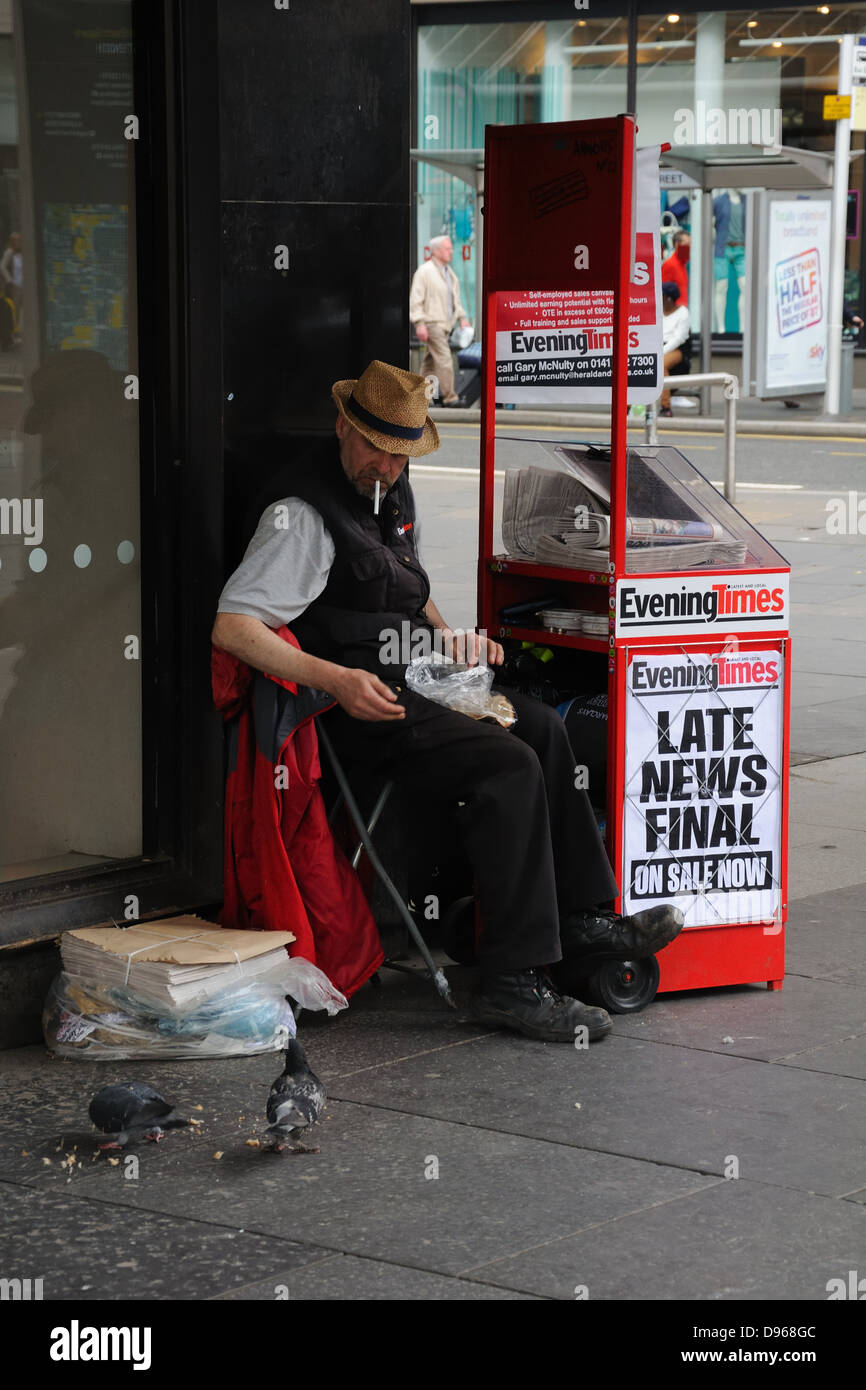 Newspaper vendor feeding pigeons in St Enoch Square, Glasgow, Scotland, UK Stock Photo