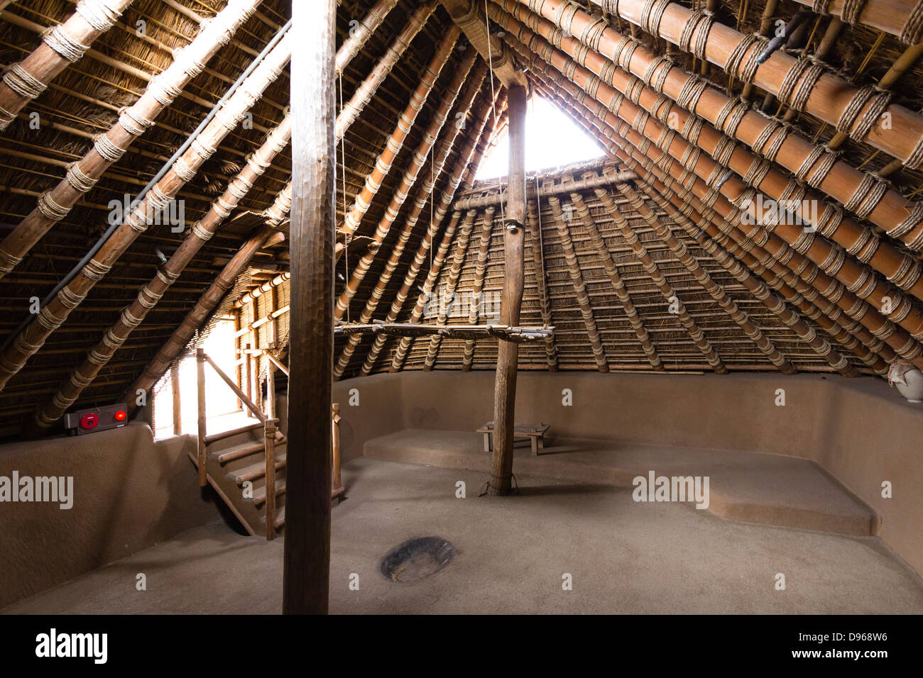 Interior of a  Yagoi period pit house dwelling at the Yoshinogari Park in Japan. Stone age thatched roof structure with earthen sides and floor. Stock Photo