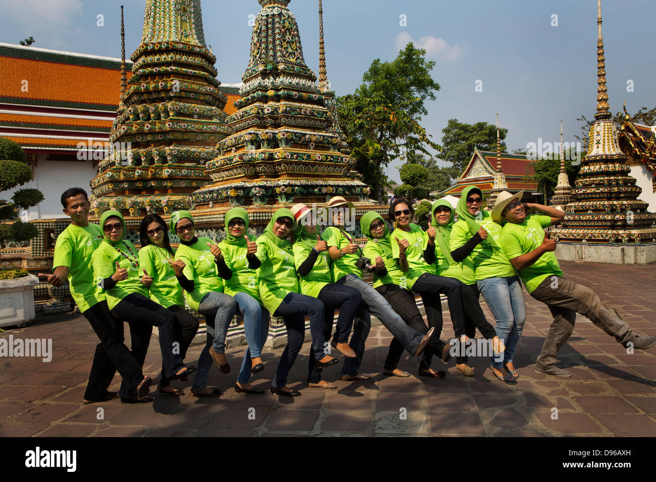 Muslim workers from an insurance company all dressed in branded Tshirts pose for a group shot inside the temple of Wat Pho in Ba Stock Photo