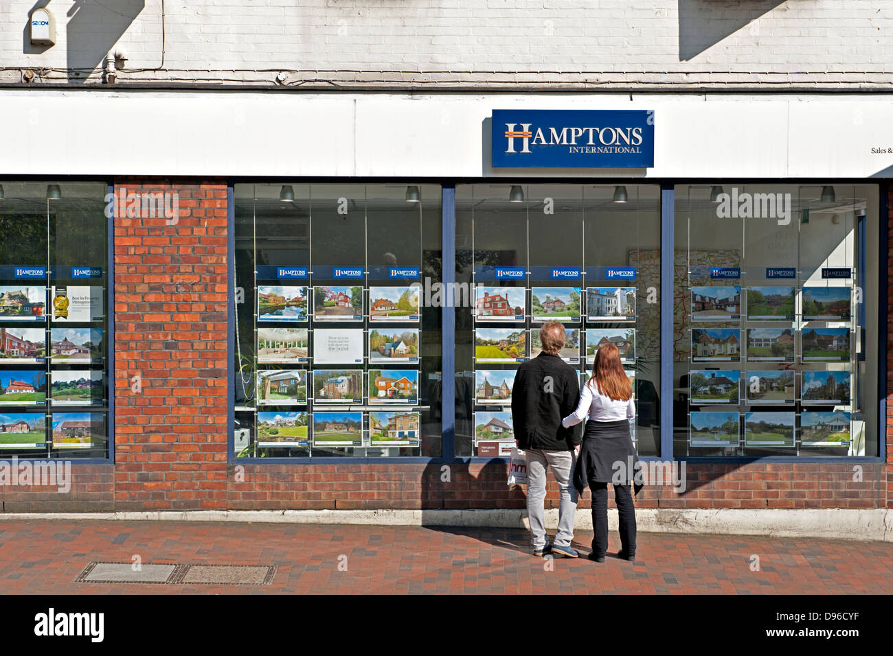 A young couple looking at property descriptions at an estate agent. UK