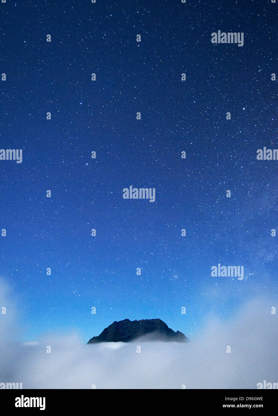 Night-time view of the Piton des Neiges peak (3071m) poking above the cloud on the French island of Reunion in the Indian Ocean. Stock Photo
