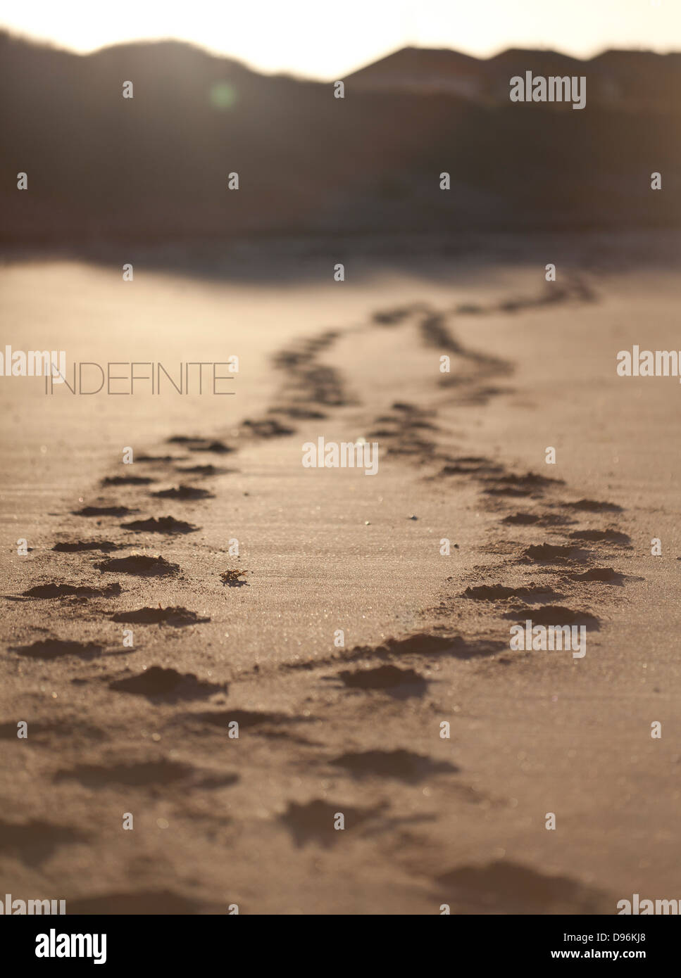 Roland Barthes inspired text and images project. Indefinite beside pair of footprints on sandy beach at sunset. Stock Photo