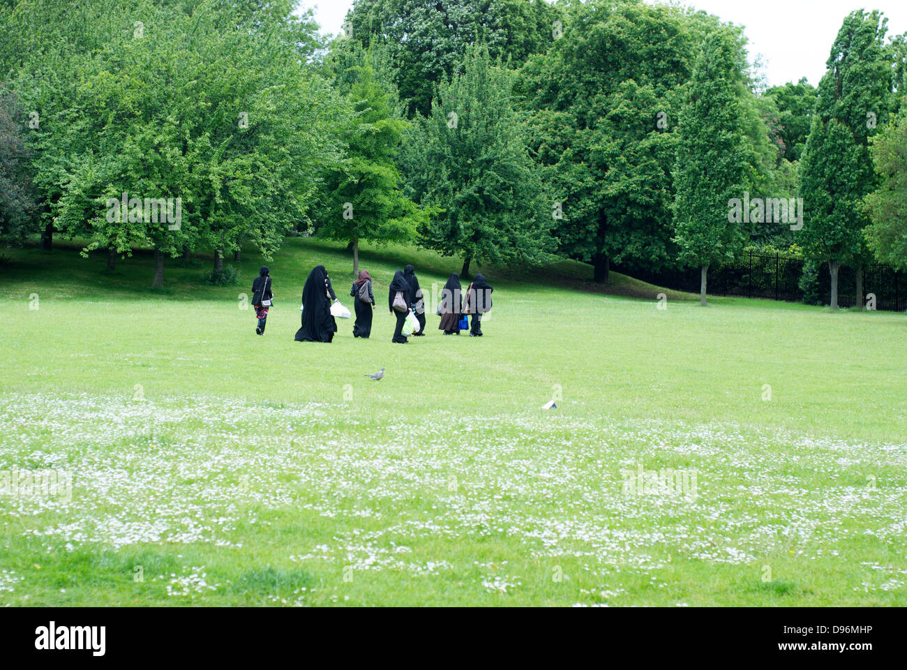 A group of muslim women walking across a park wearing burkhas Stock Photo