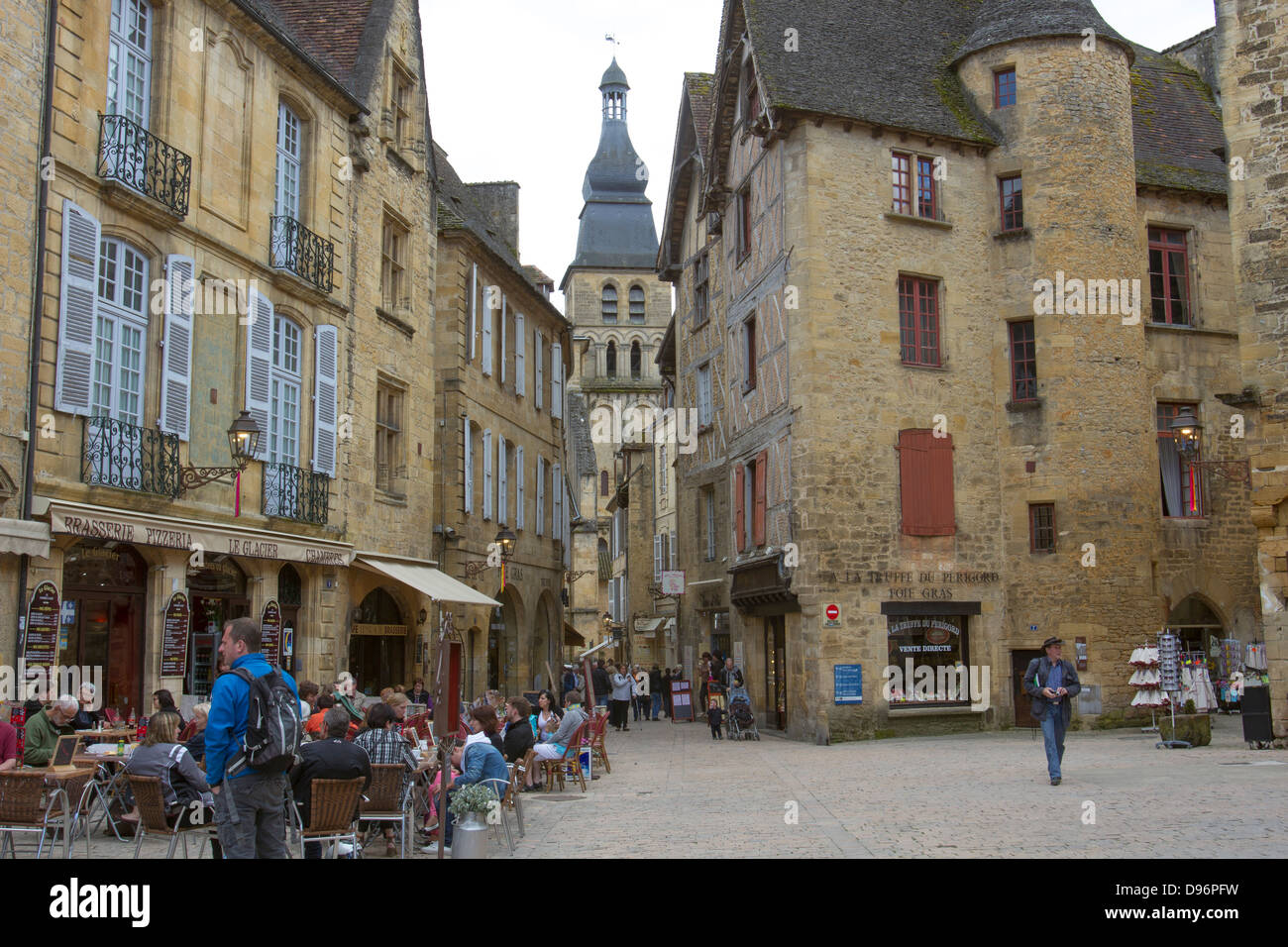 Tourists eating and shopping in Liberty Plaza by bell tower of Cathedreal Saint-Sacerdos in medieval town of Sarlat, France Stock Photo