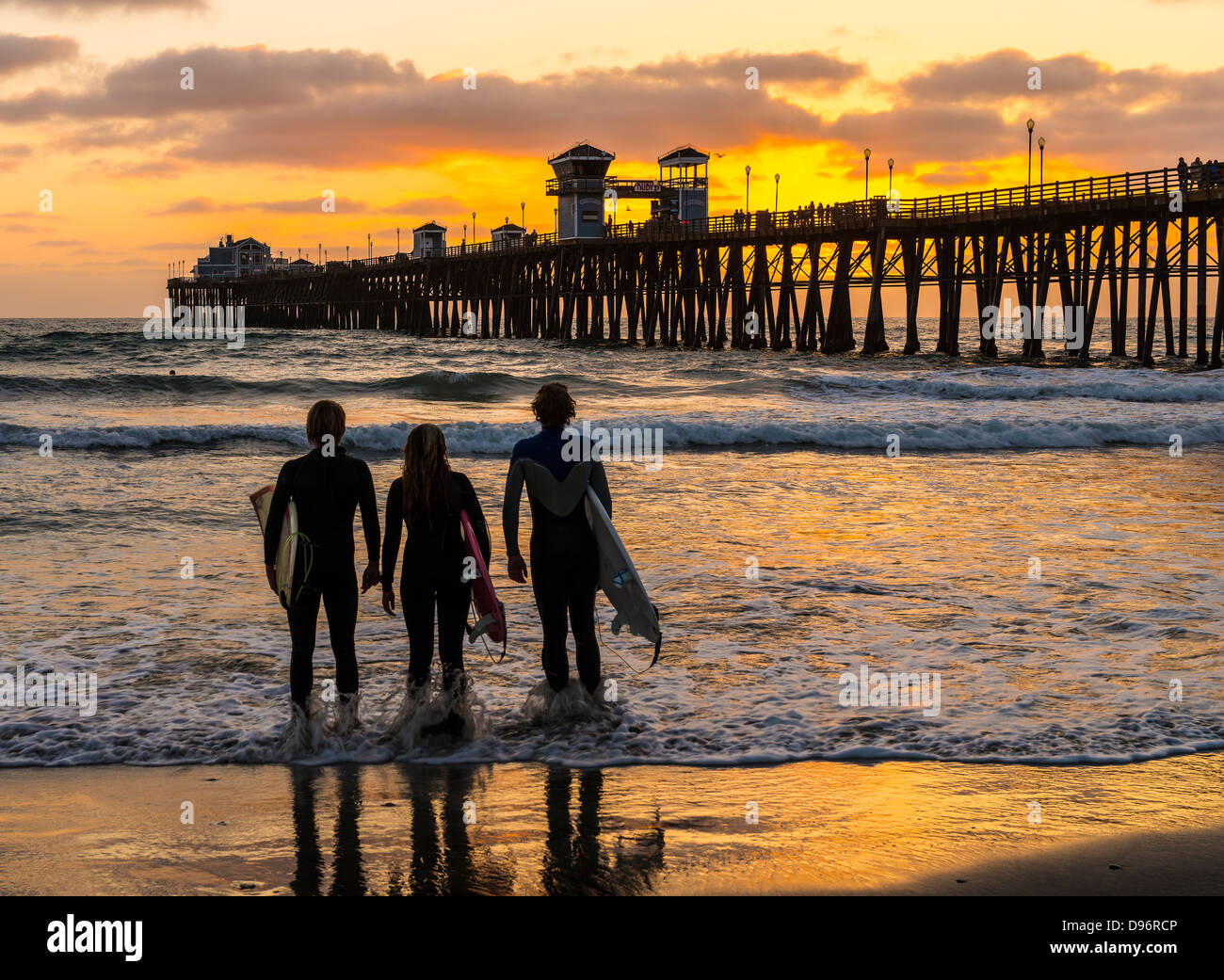 surfer friends watching a sunset in oceanside california stock