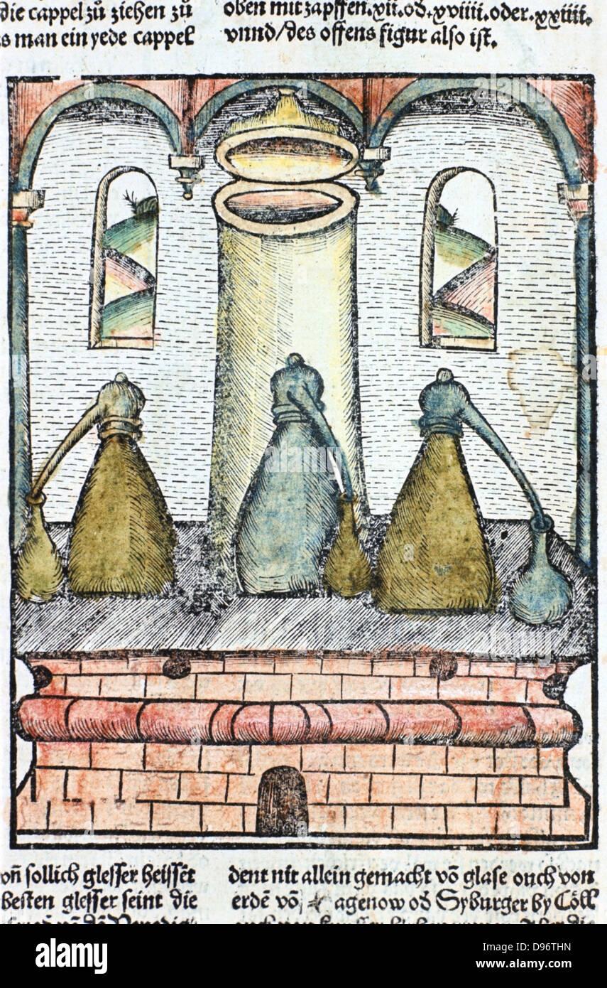 Distillation 1500. Three alembics stand on top of furnace. The distillate condenses in caps on top of vessels and flows down into collecting bottles. The pillar in the centre of the furnace is for refuelling. From ' Liber de arte distillandi de simplicibus' by Hieronmus Braunschweig. (Strasbourg, 1500). Stock Photo
