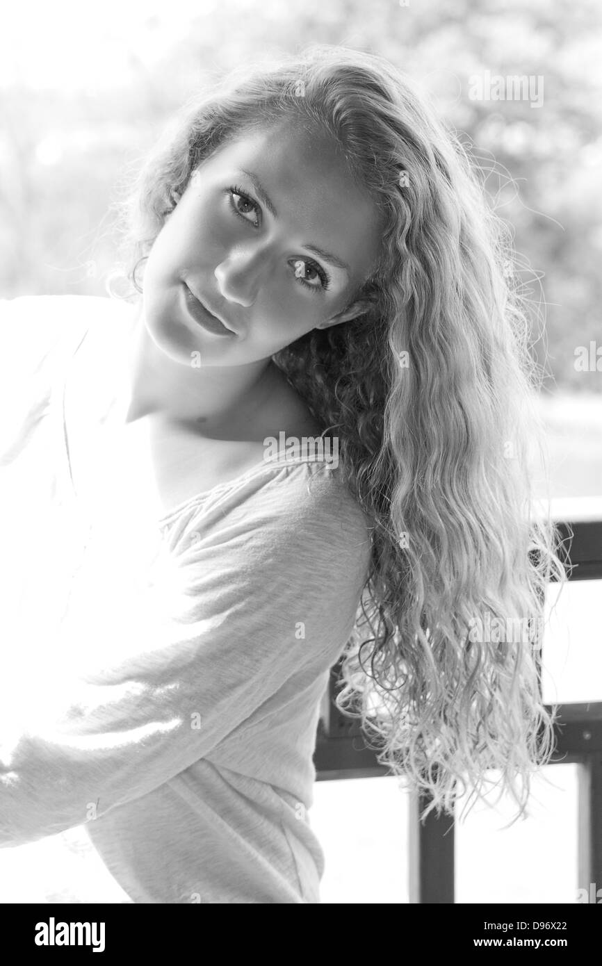 Beautiful young woman with long curly hair leans head back and smiles ...